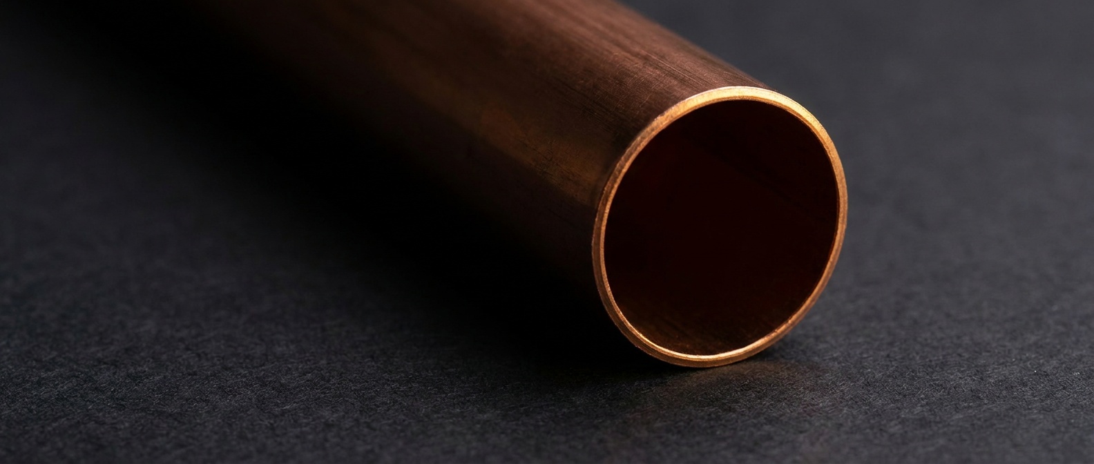 Close detail of a copper pipe end catching warm light